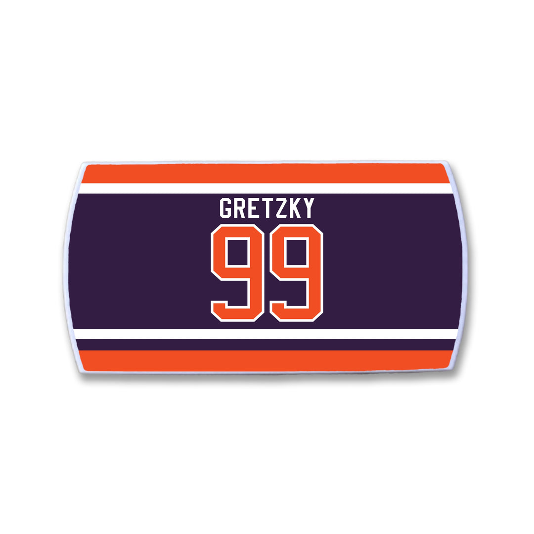 A rectangular ZippyBack™ patch with dark blue, orange, and white stripes, featuring "Wayne Gretzky" and the number 99 in bold orange and white— a Limited Edition tribute to hockey’s greatest.