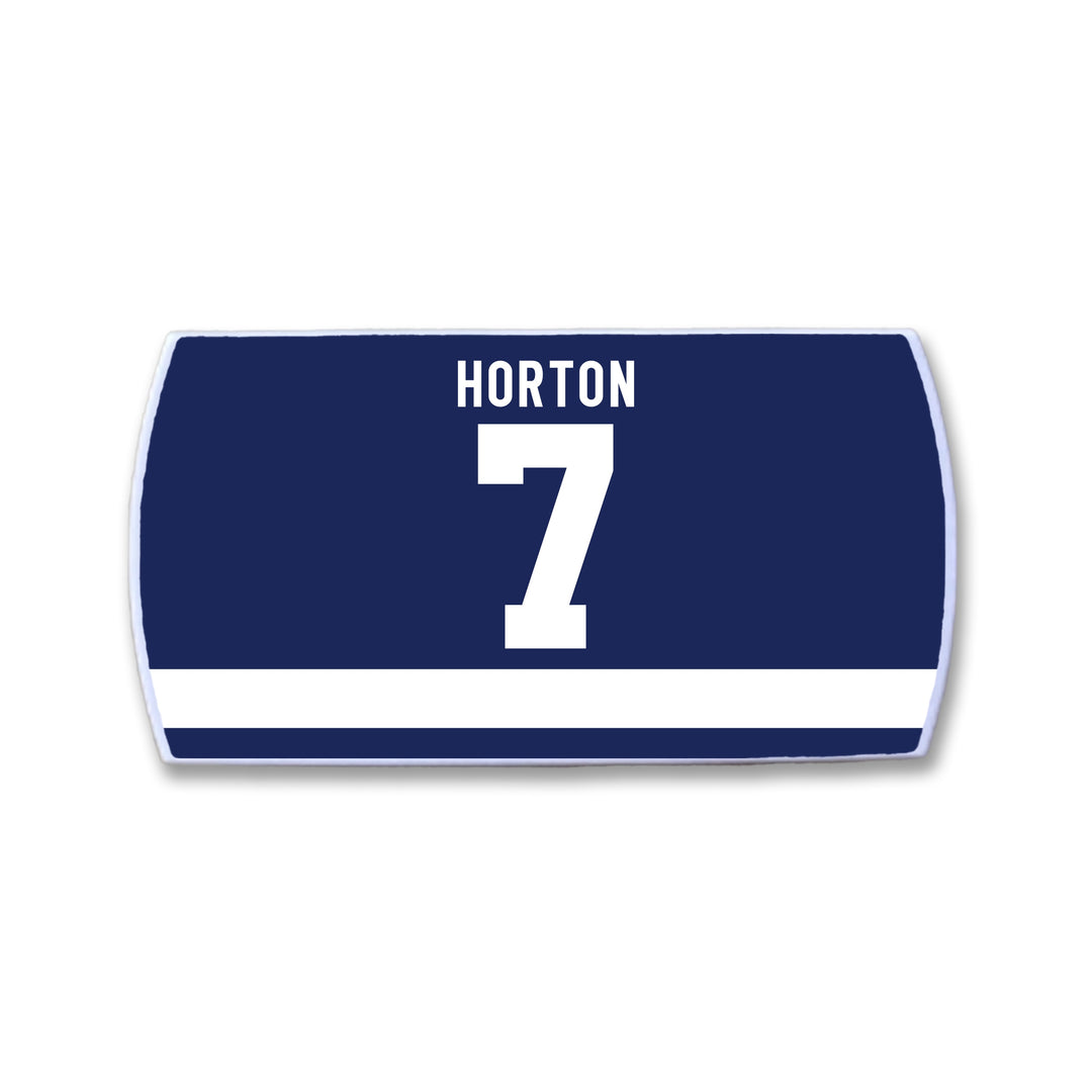 The ZippyBack™ Tim Horton navy blue rectangular hockey jersey nameplate features a white HORTON 7 and a horizontal white stripe near the bottom, honoring defenseman Tim Horton.
