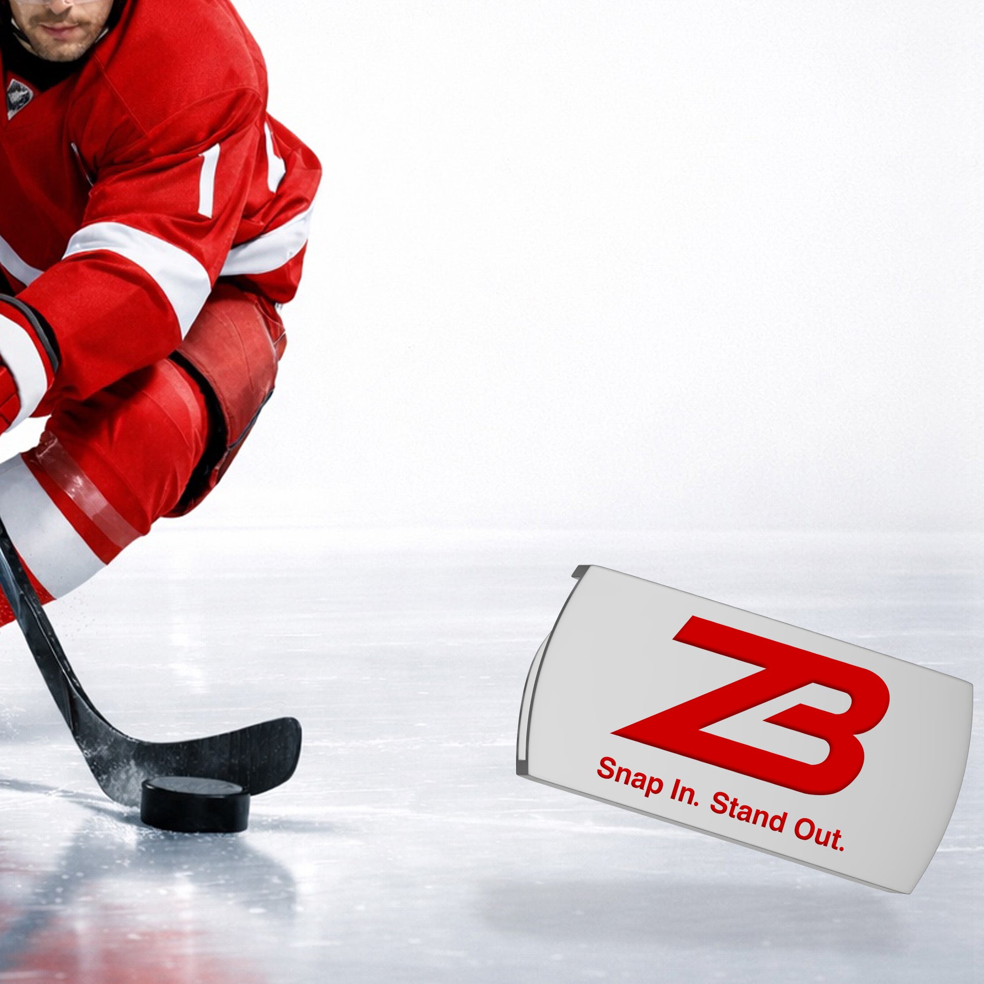 A hockey player in red uniform skates on ice, closely handling a puck with a stick. In the foreground, a white object with a red ZB logo and the text Snap In. Stand Out. is displayed.