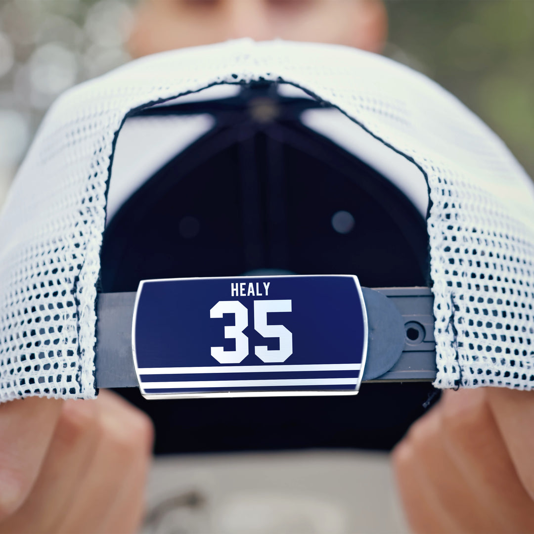 Close-up of a person holding a white mesh ZippyBack™ Glenn Healy baseball cap, with the adjustable strap facing the camera and a blue label showing “HEALY” above the number “35,” honoring NHL goalie Glenn Healy’s career.