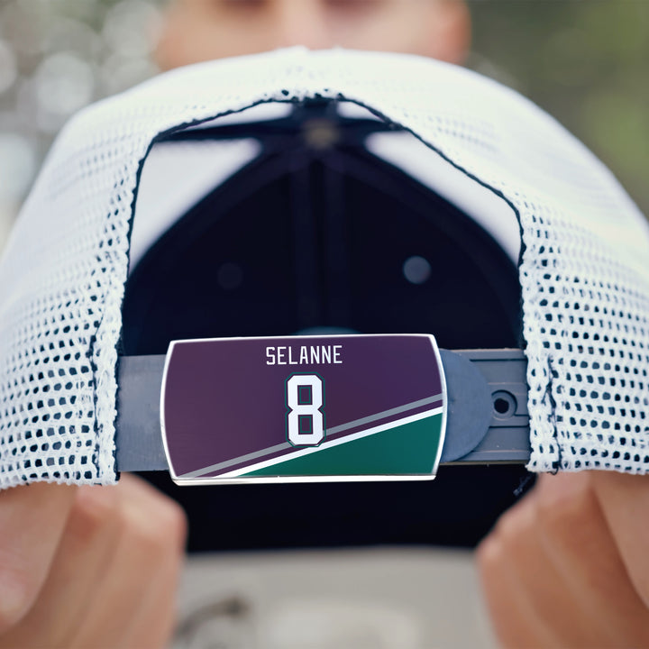 A close-up of the back of a white mesh ZippyBack™ baseball cap features a label with "Teemu Selänne" and the number 8 on a maroon, green, and white background.