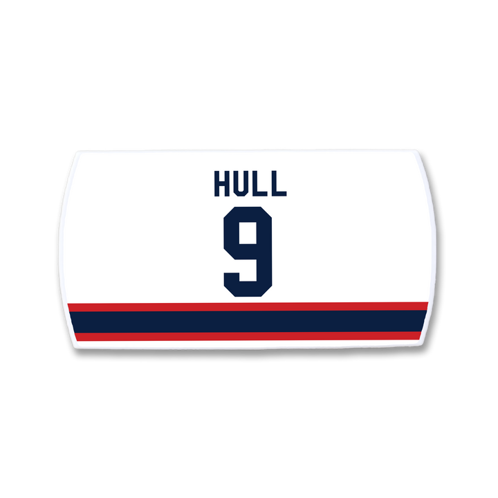 Celebrate Bobby Hull with a ZippyBack™ white hockey jersey nameplate featuring "HULL" and the number 9 in navy blue, above red and navy stripes—honoring the legendary scorer.