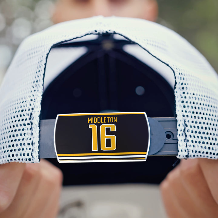 A person holds the back of a white mesh ZippyBack™ Rick Middleton baseball cap, displaying a label with MIDDLETON 16 in yellow and white letters, honoring the standout winger.