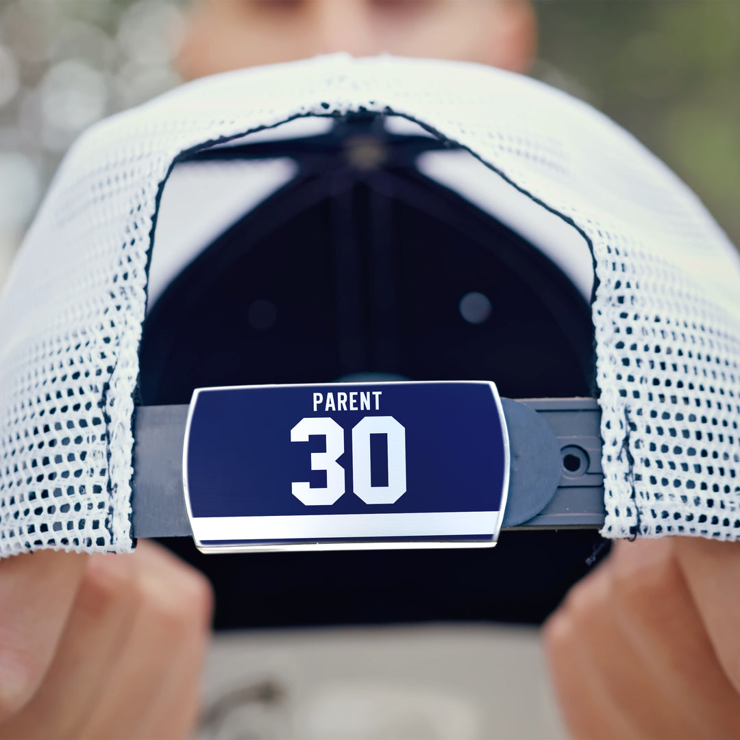A close-up of a person holding a white ZippyBack™ mesh baseball cap named "Bernie Parent," highlighting its adjustable strap with a blue label reading PARENT 30. The face is out of focus in the background.