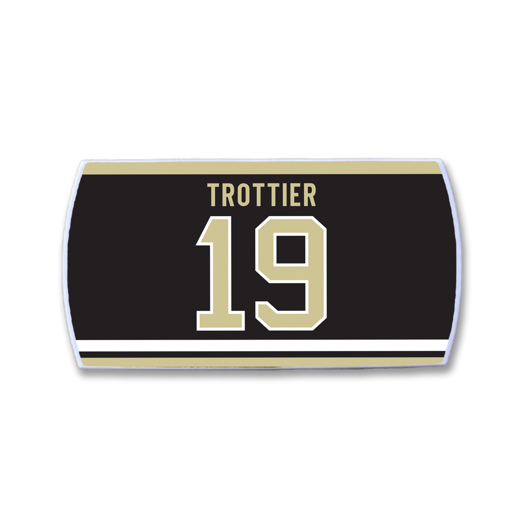 A ZippyBack™ rectangular patch honors Bryan Trottier, featuring a black background with "TROTTIER" in gold above the number 19, both outlined in white and bordered by gold and white stripes.