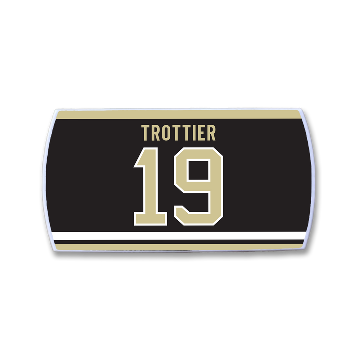 A ZippyBack™ rectangular patch honors Bryan Trottier, featuring a black background with "TROTTIER" in gold above the number 19, both outlined in white and bordered by gold and white stripes.