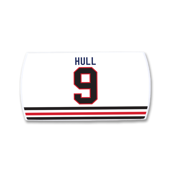 A ZippyBack™ Bobby Hull white hockey jersey features "HULL" in blue, the number 9 in black and red, and two black-red stripes near the bottom—a tribute to the legendary goal scorer.