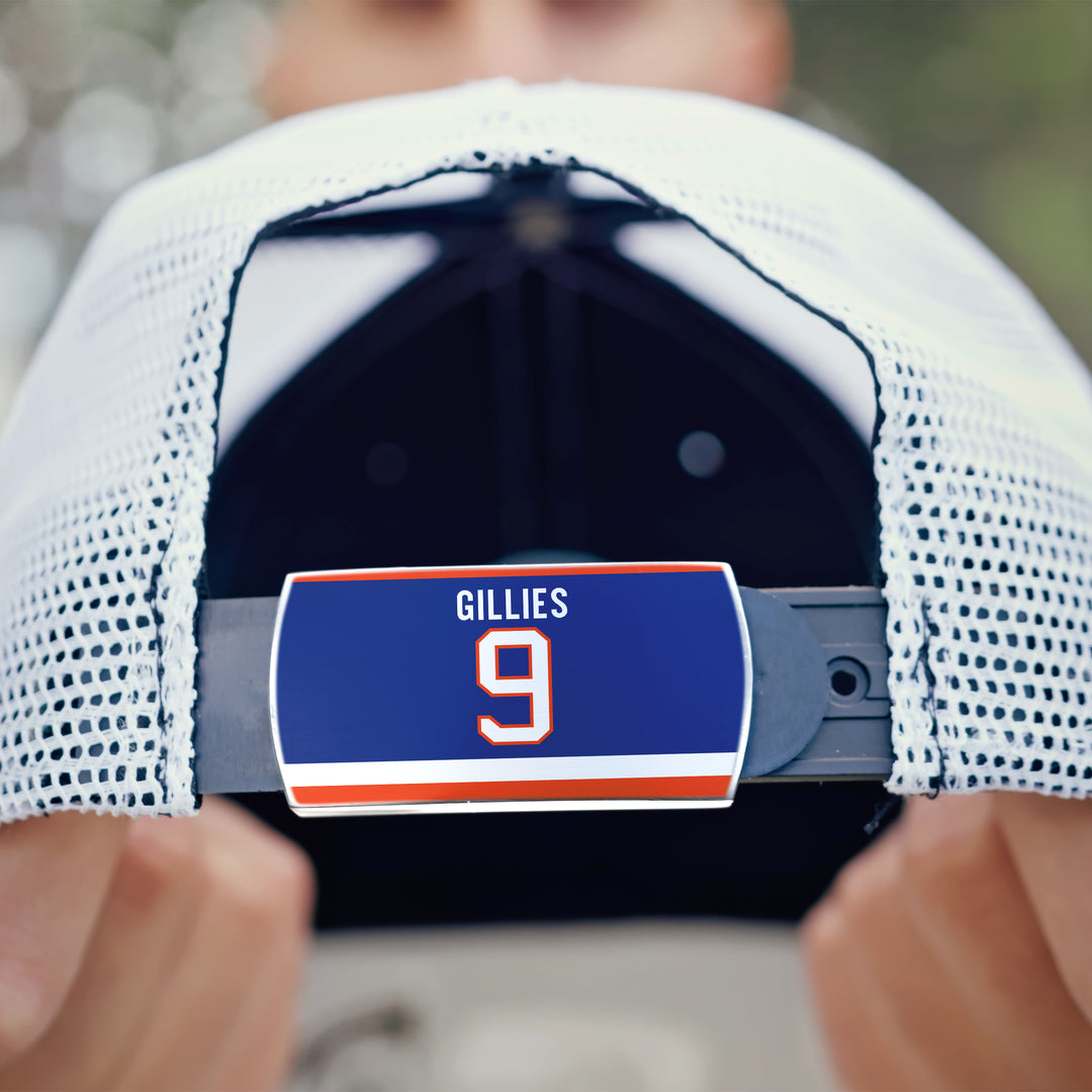 A close-up of the back of a white mesh ZippyBack™ Clark Gillies baseball cap, featuring a blue name tag with "GILLIES 9" in white and orange, held by both hands—a tribute to the legendary power forward.