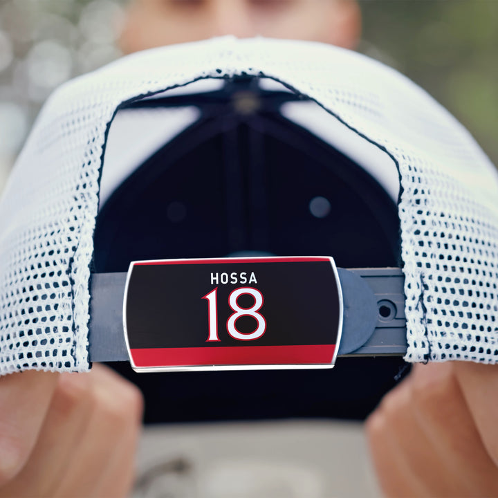 A person holds a ZippyBack™ Marian Hossa white mesh baseball cap featuring a nameplate with HOSSA 18 in bold white and red letters on a black and red background.